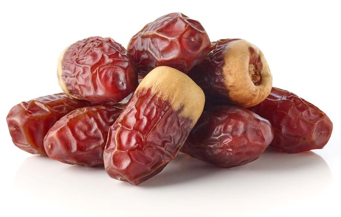 كومة من تمر الصقعي اللذيذ على خلفية بيضاء-التشافي بالغذاء