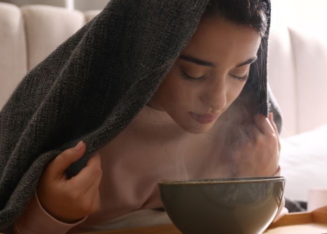 فتاة تستنشق بخار الماء بالأعشاب للتخلص من البلغم-التشافي بالغذاء