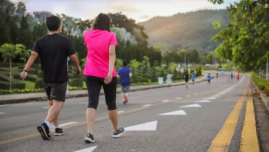 امرأة ورجل يمارسان رياضة المشي في أحد الشوارع-التشافي بالغذاء