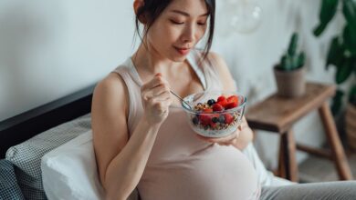 امرأة حامل تتناول طبق من السلطة مع الزبادي والفراولة-التشافي بالغذاء