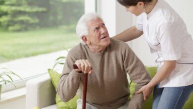 ممرضة لطيفة تساعد رجل مصاب بمرض باركنسون-التشافي بالغذاء