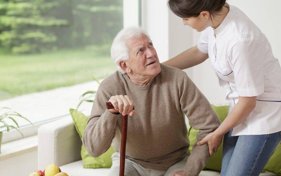 ممرضة لطيفة تساعد رجل مصاب بمرض باركنسون-التشافي بالغذاء