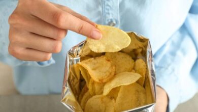 فتاة تحمل بيدها كيس بطاطس مقلية وتتناولها-التشافي بالغذاء